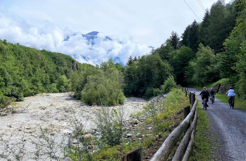 Etsch mit Hochwasser neben einer Gruppe Fahrradfahrer