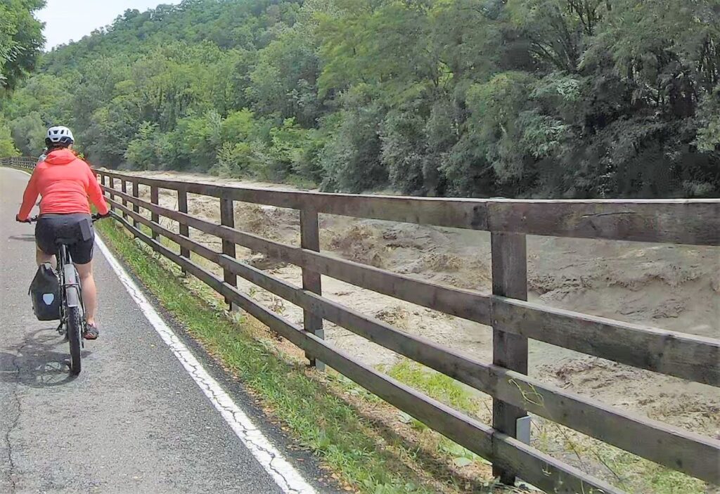 Radfahrerin neben tosender Etsch