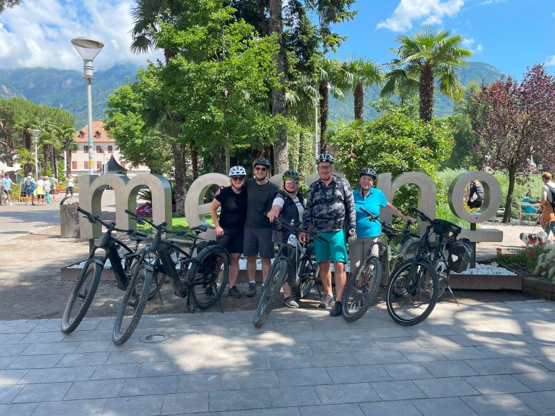 Gruppe Radfahrer vor Schriftzug in Meran