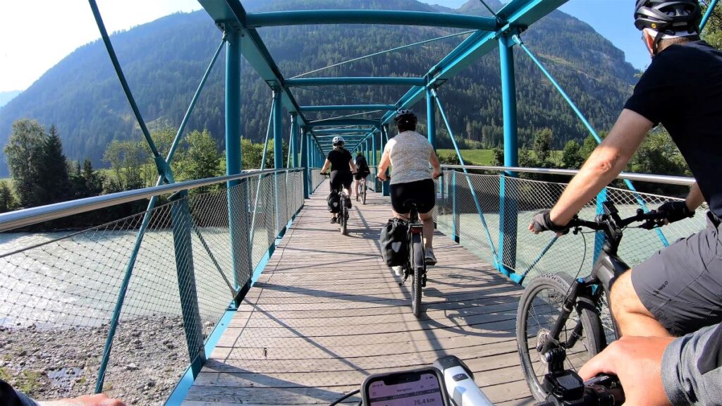 Gruppe Fahrradfahrer auf einer Brücke über den Inn bei Pfunds