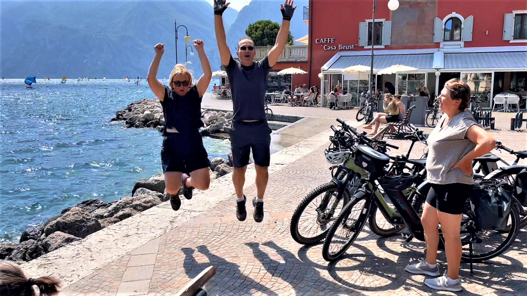 Radfahrer am Ufer des Gardasees in Torbole springen in die Luft