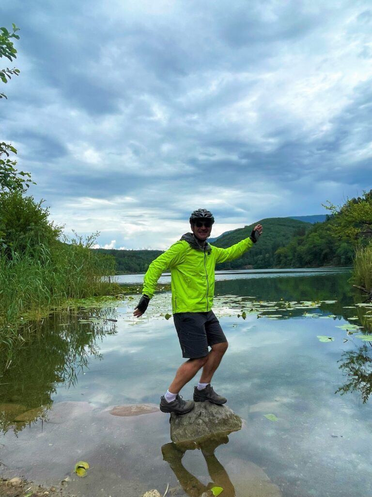 Radfahrer balanciert auf Felsen im Montiggler See