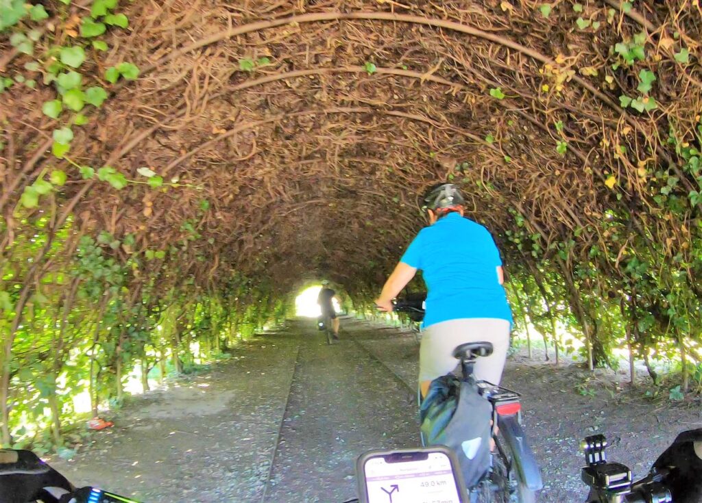 Radfahrerin fährt durch eine bepflanzte Röhre