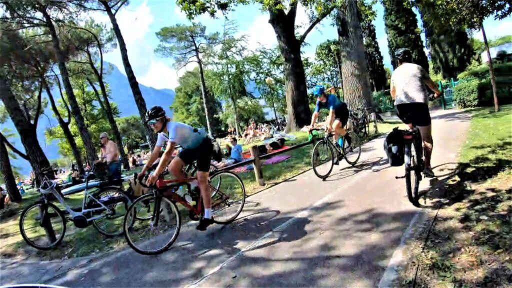 Belebte Uferpromenade mit zahlreichen Radfahrern in Torbole