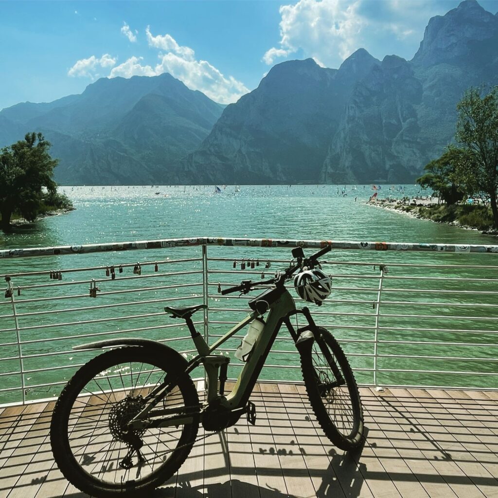 E-Mountainbike auf Brücke mit Gardasee im Hintergrund in Torbole