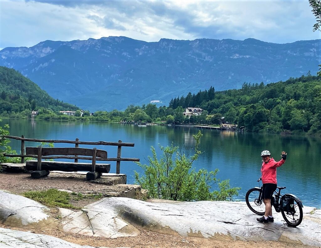 Fahrradfahrerin vor Panorama vom Montiggler See