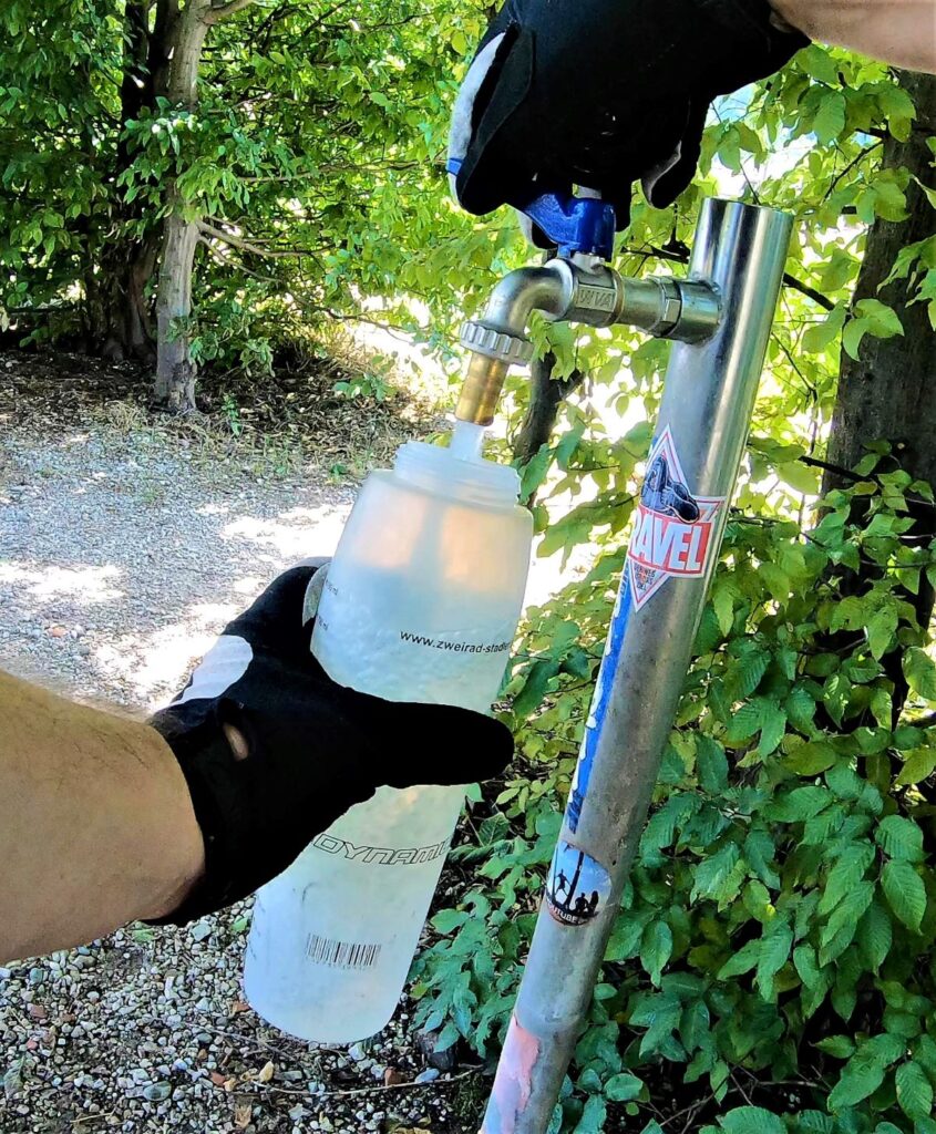 Radfahrer füllt Flasche mit Wasser